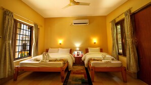 A hotel room with two single beds, a ceiling fan, an air conditioning unit, and a window with curtains. - Chitwan Paradise Hotel (Sauraha)