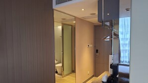 Een moderne hotelkamer met een schuifdeur naar een badkamer, een klein kitchenette en uitzicht op buiten.