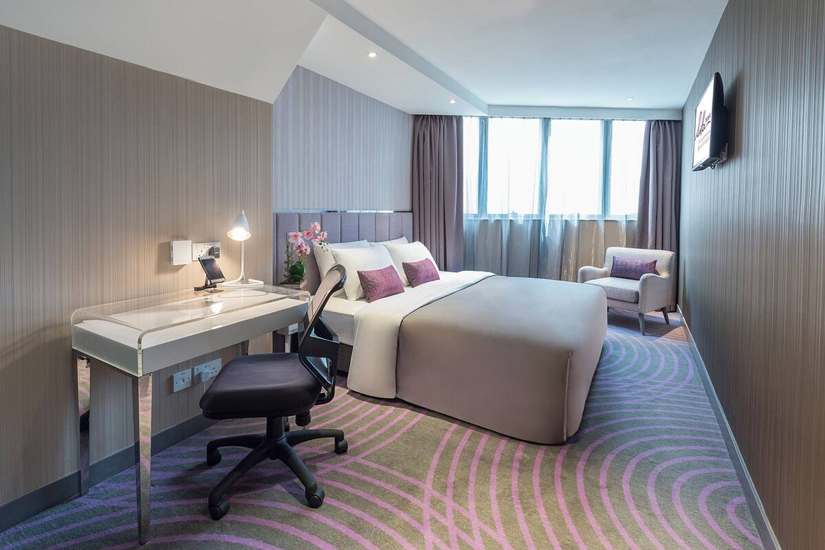 Ein Hotelzimmer mit Bett, Schreibtisch, Stuhl und einem großen Fenster.