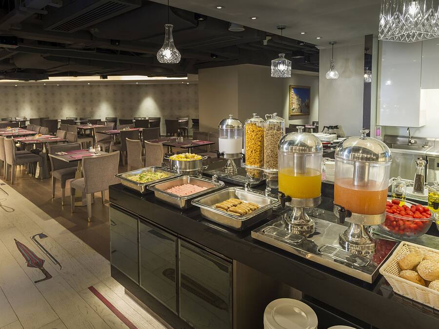 A buffet setup with various food items and beverages, including a fruit bowl and a juice dispenser.