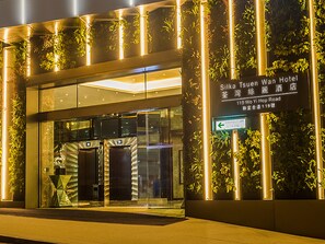 The exterior of the Silka Tsuen Wan Hotel with a modern glass facade, vertical garden, and illuminated signage. - Silka Tsuen Wan Hong Kong (Kwai Chung)