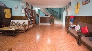 Un salón amplio con suelo de madera, un sofá, una mesa de centro y una escalera que sube a un nivel superior.