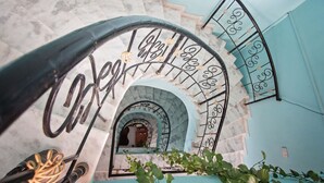 Una escalera de mármol con barandillas de metal y un arco decorativo.