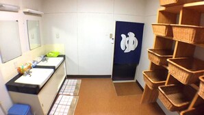 A bathroom with two sinks, a mirror, a blue door with a white symbol, and wicker baskets on shelves. - Resort Ryokan Yadokari (Echizen)