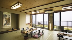 A traditional Japanese room with tatami flooring, a low table, cushions, and a large window offering a view of the sea. - Resort Ryokan Yadokari (Echizen)