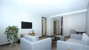 A modern hotel room with a sofa, a small table, a potted plant, and a flat-screen TV mounted on the wall. - ECHARM Hotel Zhengzhou High Tech Zone (Zhengzhou)