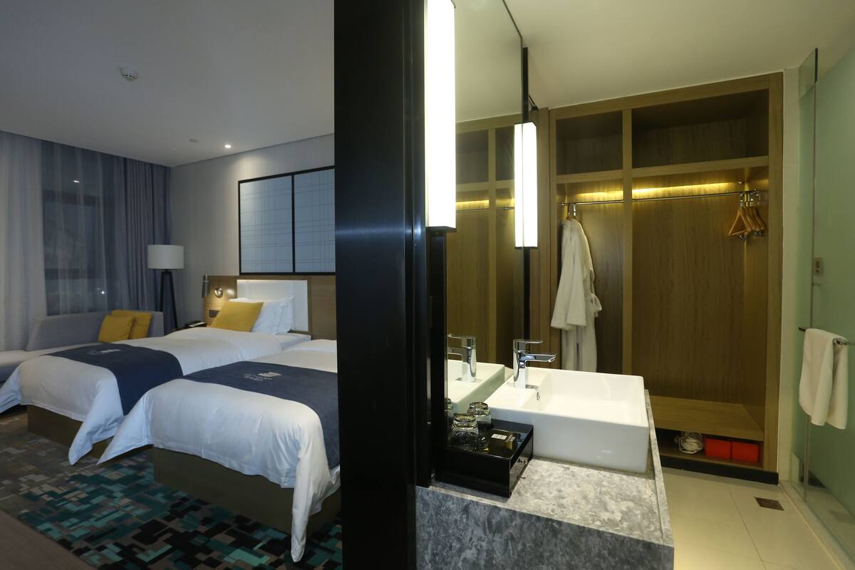Een hotelkamer met twee bedden, een badkamer met een bad en een inloopkast.