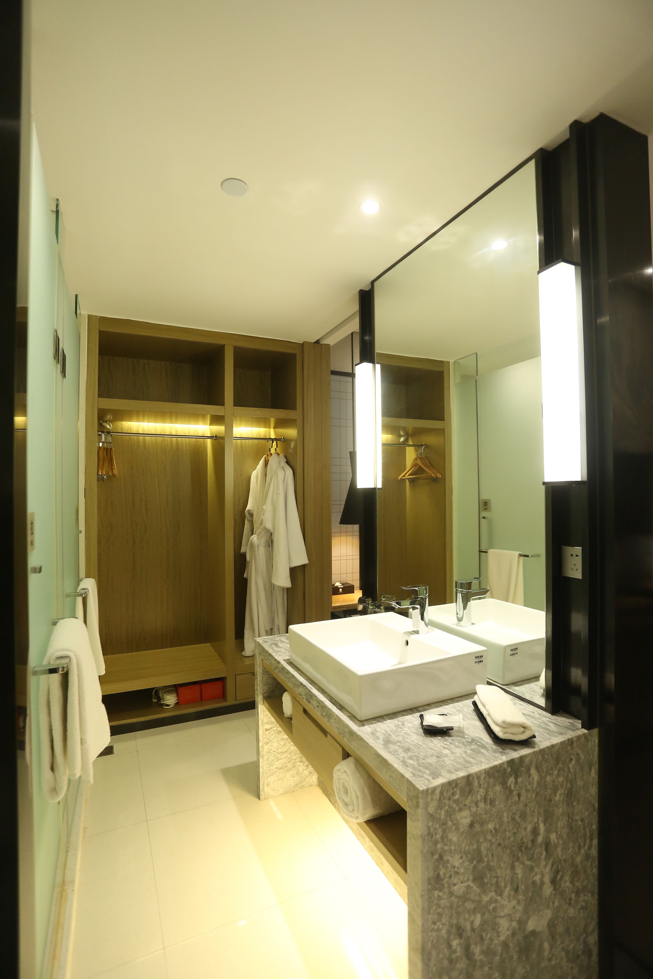 A modern bathroom with two sinks, a walk-in shower, and a large mirror.