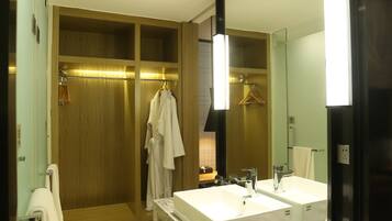 A modern bathroom with two sinks, a walk-in shower, and a large mirror.