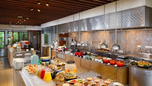 A buffet with a variety of food items and beverages, a large stainless steel range hood, and a modern kitchen design.