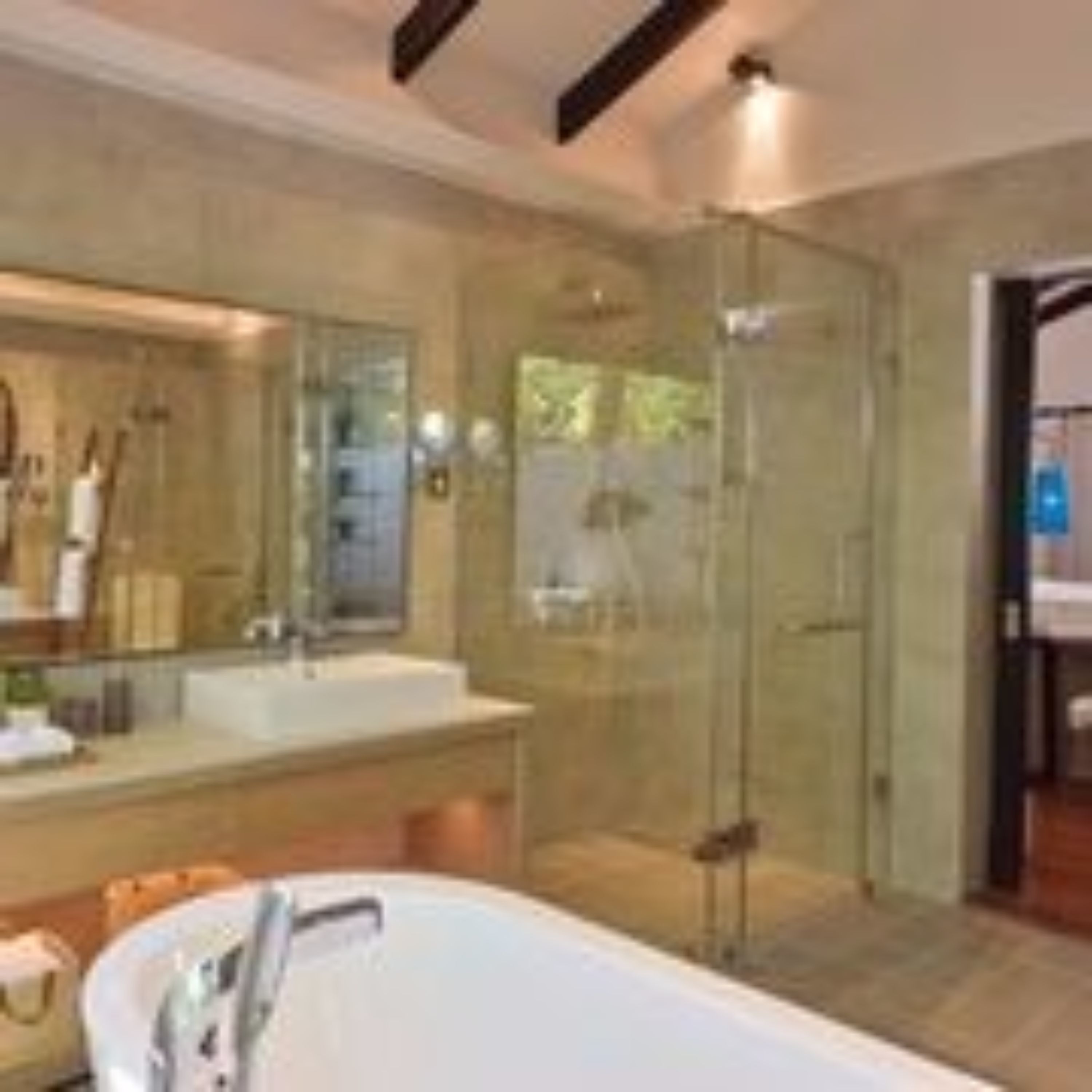 A modern bathroom with a glass-enclosed shower, a large bathtub, and a vanity with a mirror.