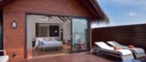 A wooden villa with a pool, a bedroom with a bed and a bathroom, and a dining area.