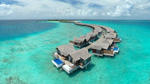 An aerial view of overwater bungalows with clear turquoise water, connected by a walkway. - Grand Park Kodhipparu (Kuda Vattaru)