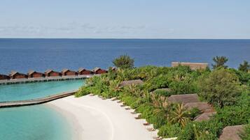 A beach resort with a white sandy shore, clear turquoise water, and overwater bungalows.