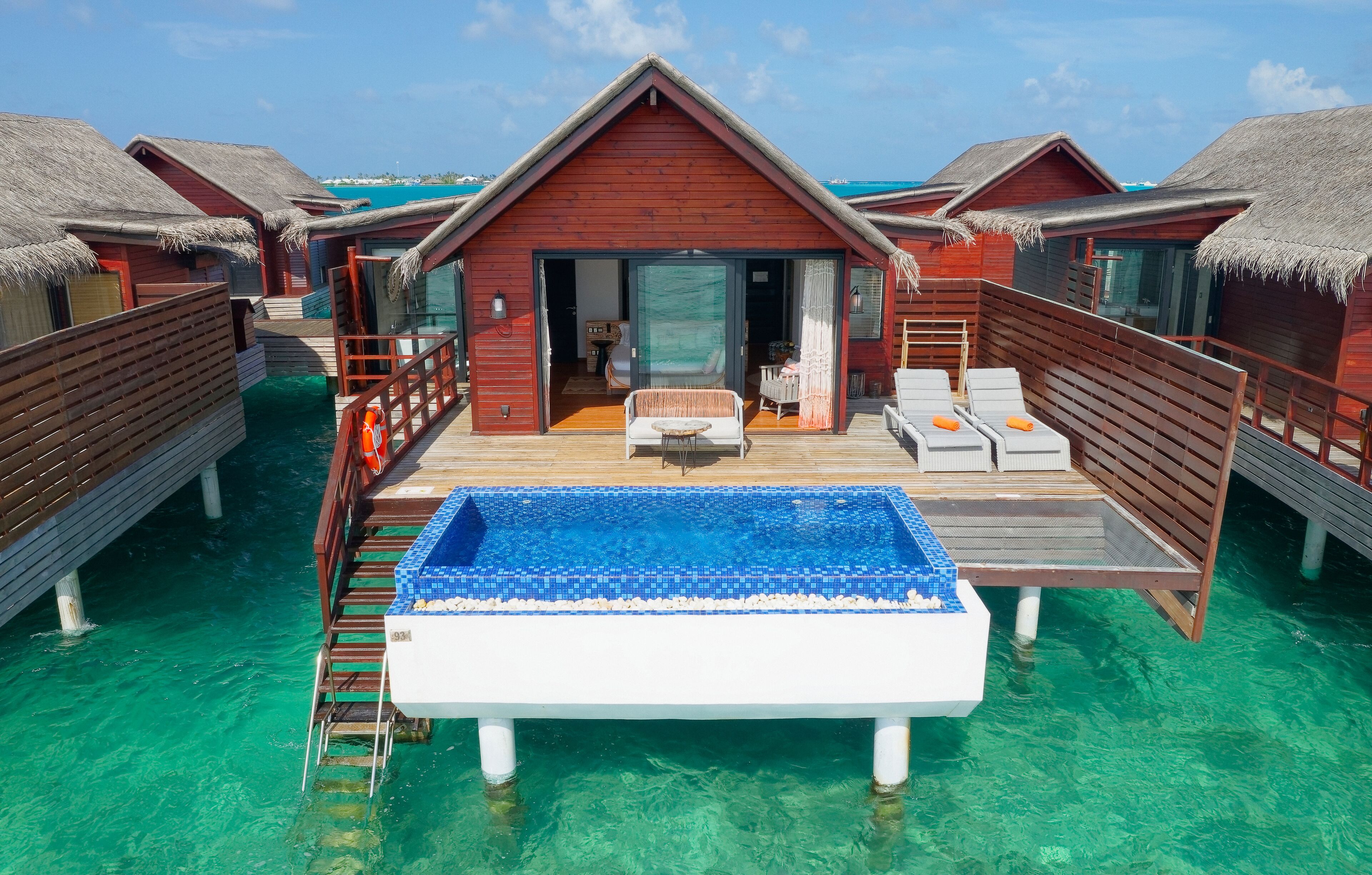 Bungalows sur pilotis dotés d’une piscine, d’une terrasse en bois et de toits de chaume.