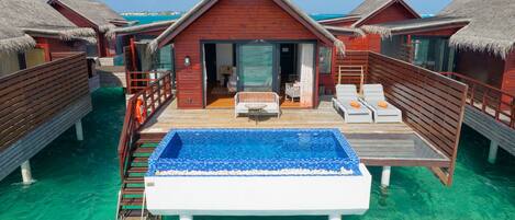 Overwater bungalows with a swimming pool, wooden deck, and thatched roofs.