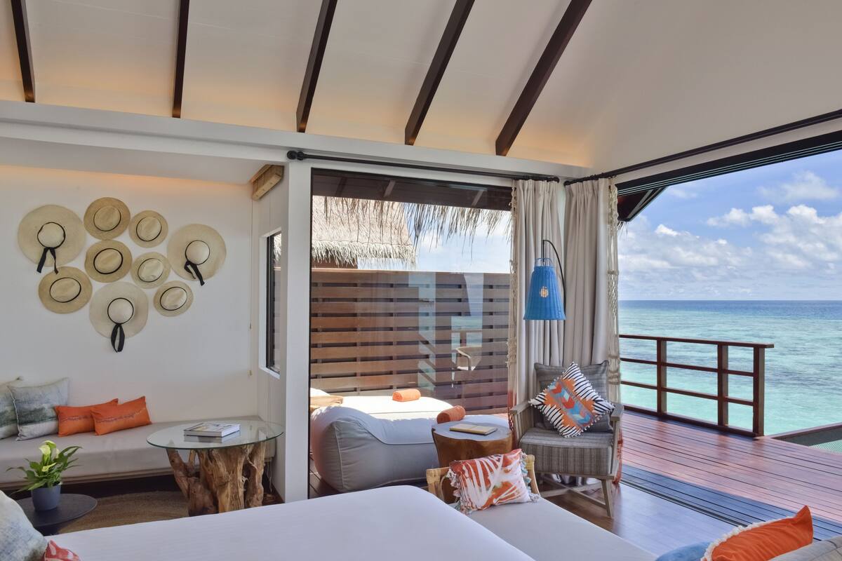 A room with a large bed, a seating area with a glass table, and a view of the ocean.