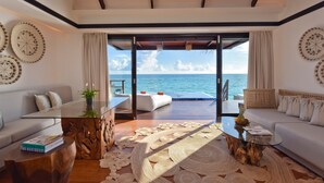 A modern living room with a glass coffee table, wooden side tables, and a view of the ocean. - Grand Park Kodhipparu (Kuda Vattaru)