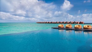 An infinity pool with overwater bungalows and lounge chairs. - Grand Park Kodhipparu (Kuda Vattaru)