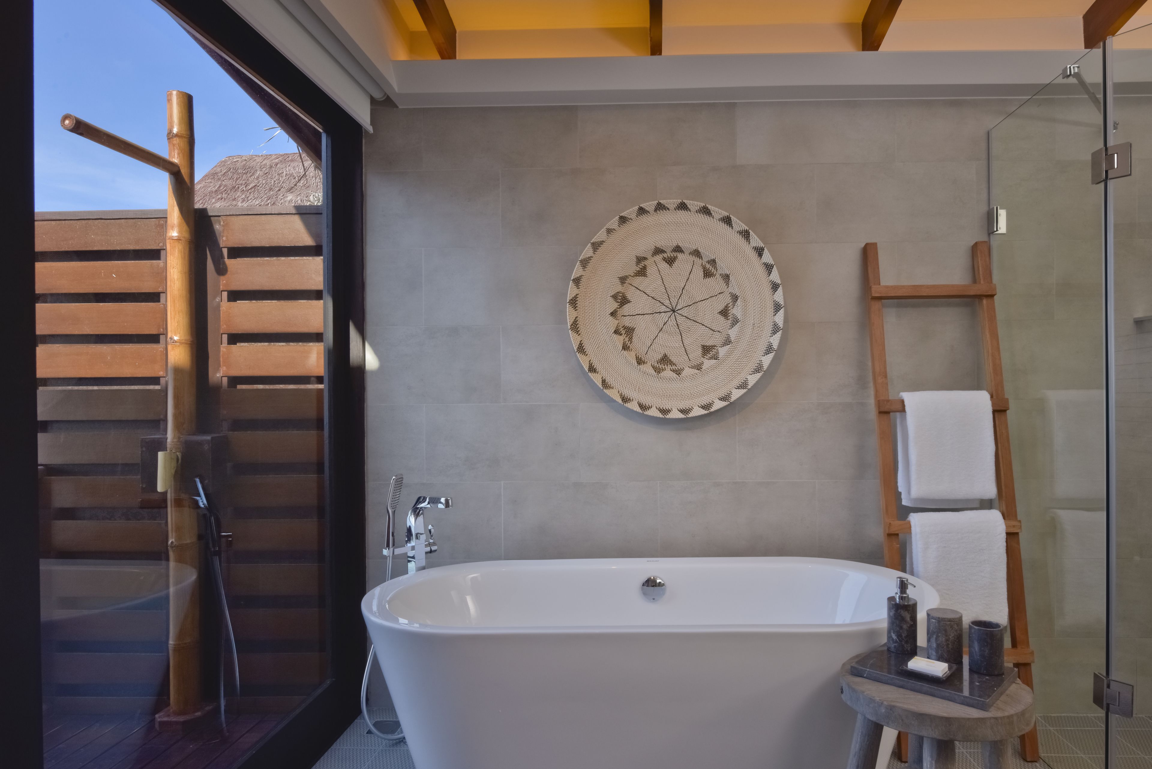 Ein modernes Badezimmer mit einer freistehenden Badewanne, einer Holzleiter und einem dekorativen Wandbild.
