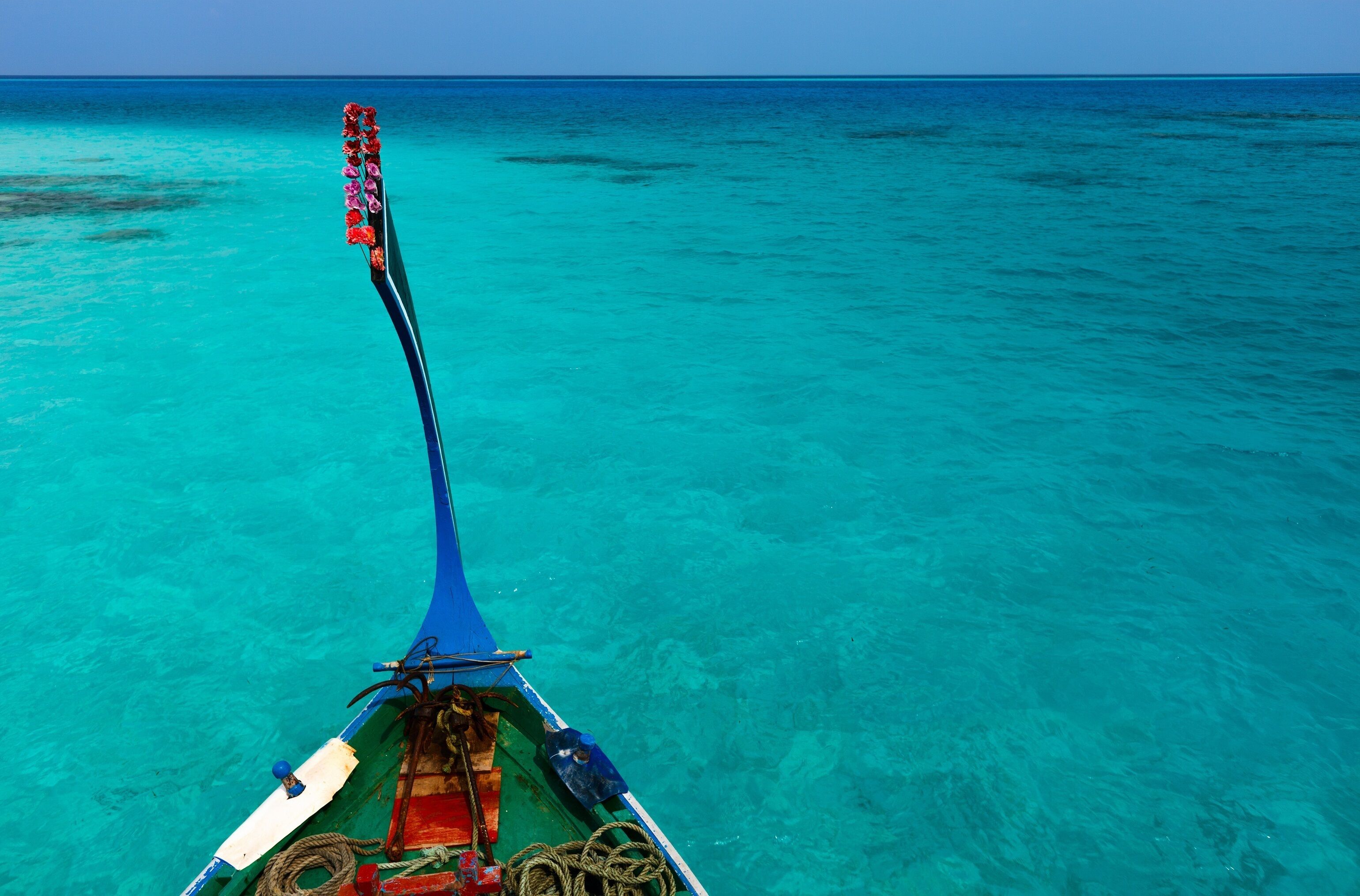 A boat with a blue canopy and a rope coiled on the deck, floating on turquoise water.