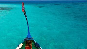 A boat with a blue canopy and a rope coiled on the deck, floating on turquoise water.