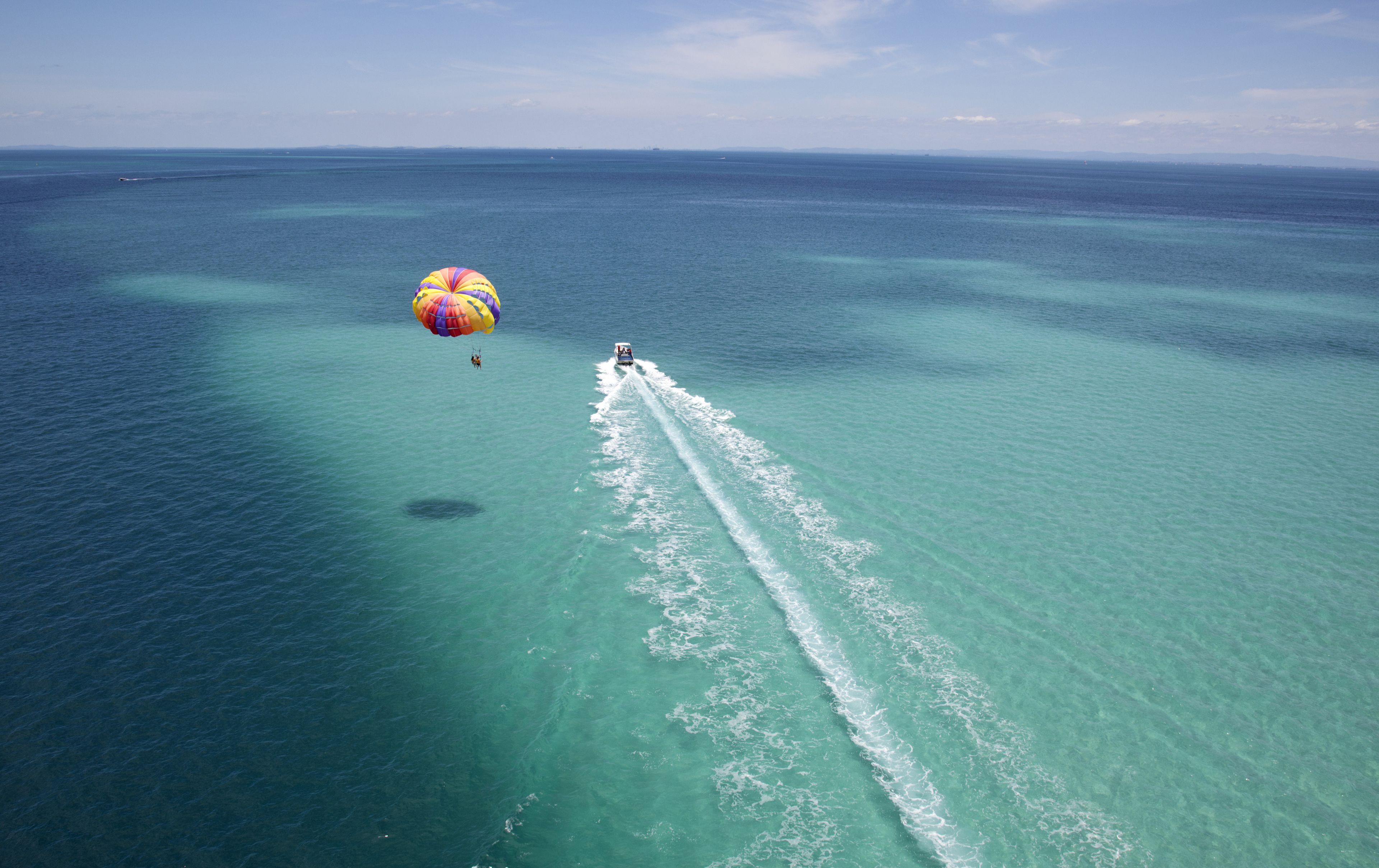 A clear view of a beach with turquoise waters and a parasail in the distance.