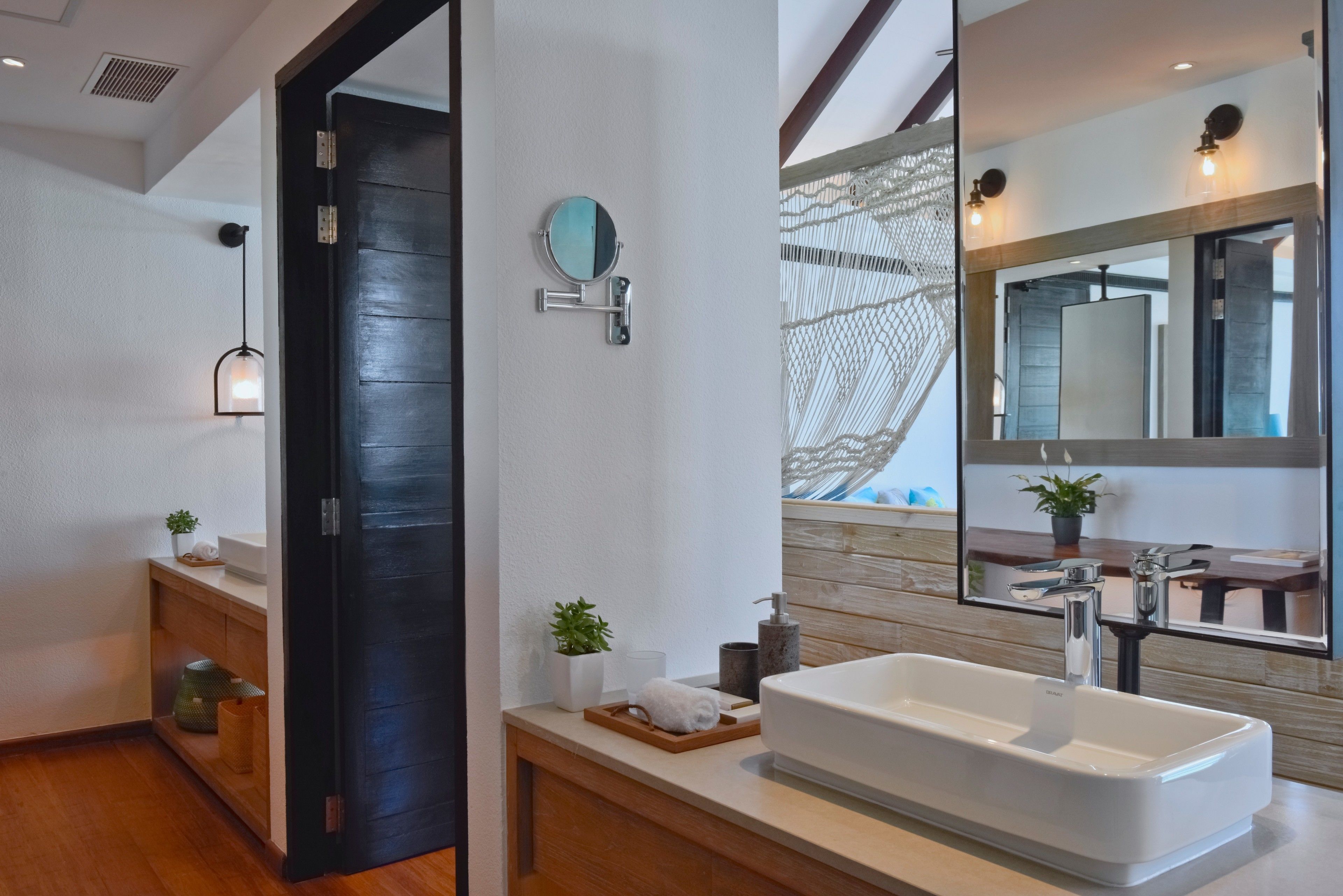 A modern bathroom with a large mirror, a white sink, and a wooden vanity.