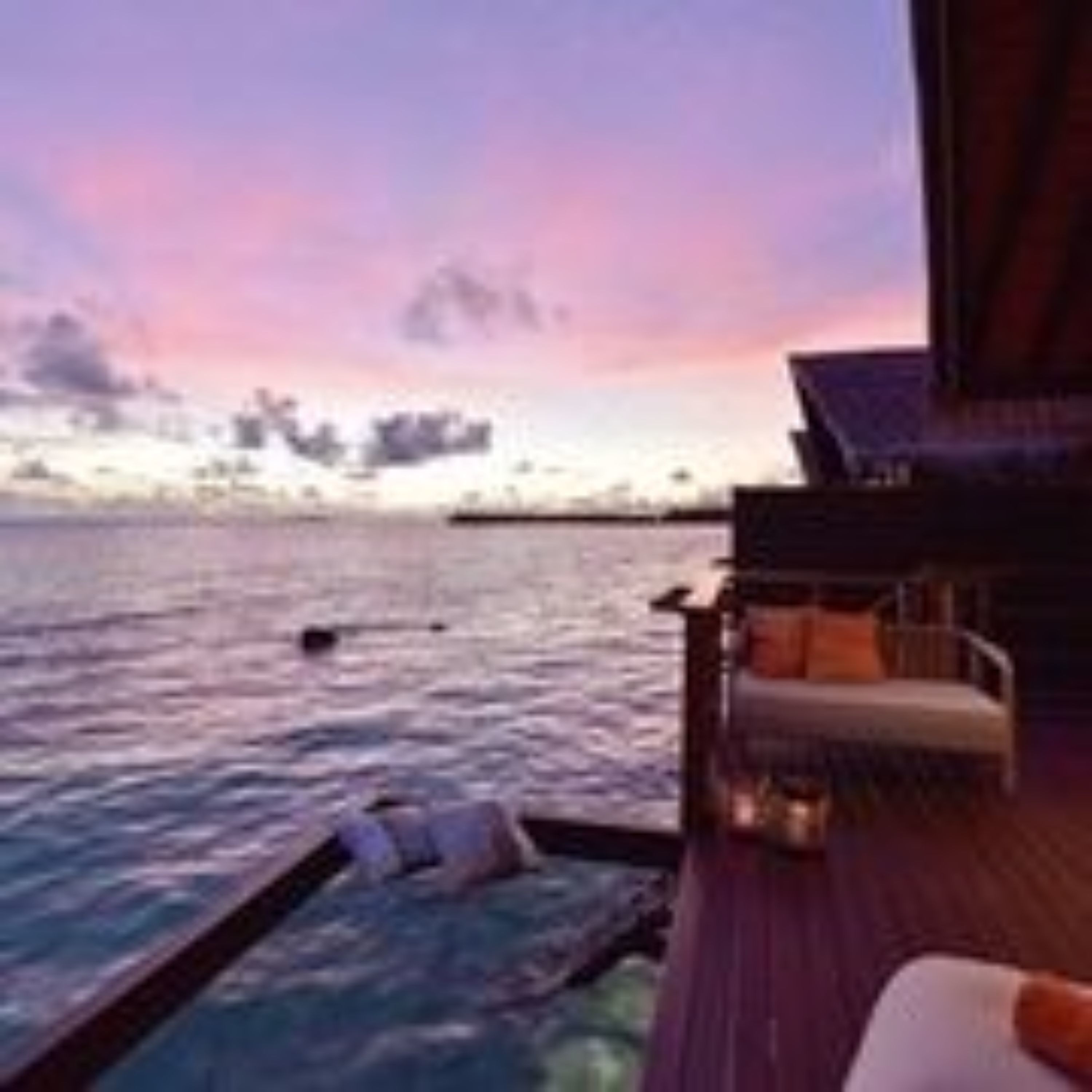 Una terraza con vista al océano y al atardecer.