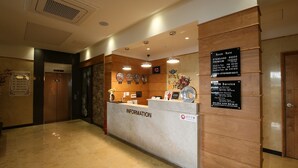 A hotel reception area with a marble counter, information signs, and a clock. - JinCheon Mini Business Hotel (Jincheon)