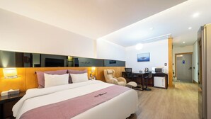 A hotel room with a large bed, a desk with a computer, a chair, and a microwave. - JinCheon Mini Business Hotel (Jincheon)