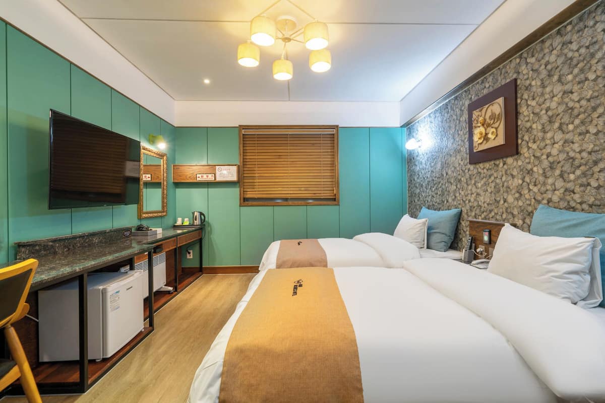 A hotel room with a bed, desk, and a television.