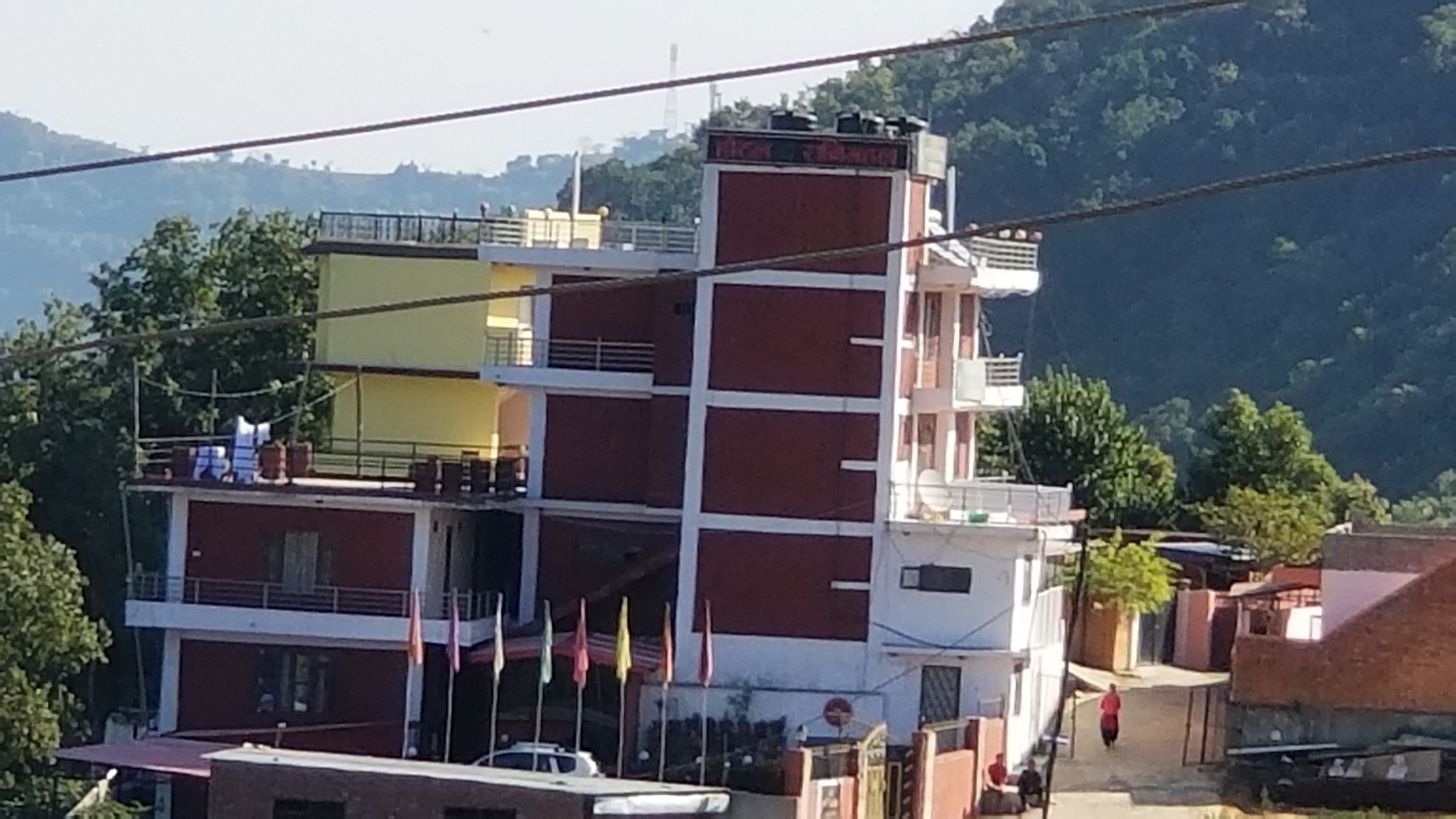A multi-story building with balconies and a flag on the ground floor.