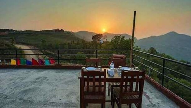 A table set outdoors with a view of the sunset and mountains in the background.