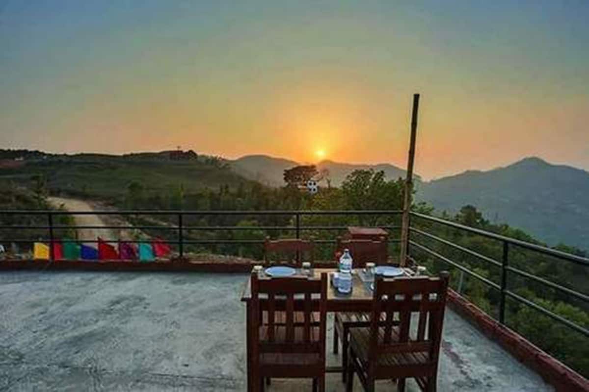 Mesa al aire libre con vista a la puesta de sol y montañas al fondo.
