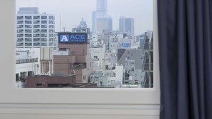 A view of a cityscape with a prominent tower, possibly a landmark, through a window with a curtain partially drawn. - Hotel Guest1 Ueno Ekimae (Tokyo)