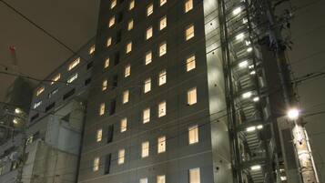 Un hotel moderno con varios pisos, una entrada destacada y una fachada bien iluminada.