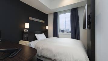 Habitación de hotel con una cama grande, un escritorio y vistas a la ciudad.