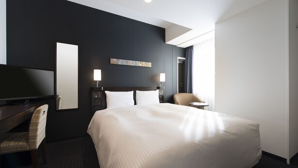 A hotel room with a large bed, a desk with a chair, a TV, two bedside lamps, and a window with curtains. - Hotel Guest1 Ueno Ekimae (Tokyo)