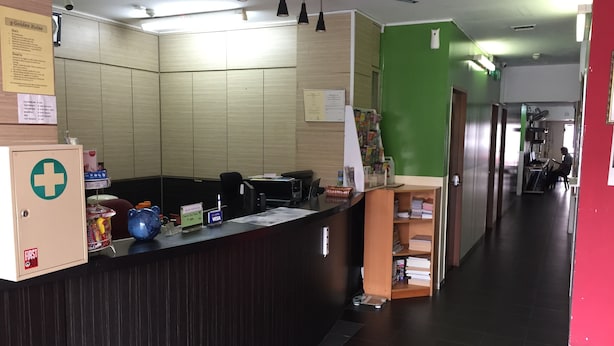 Een receptiegedeelte met een incheckbalie, een verbanddoos en een groene wand.