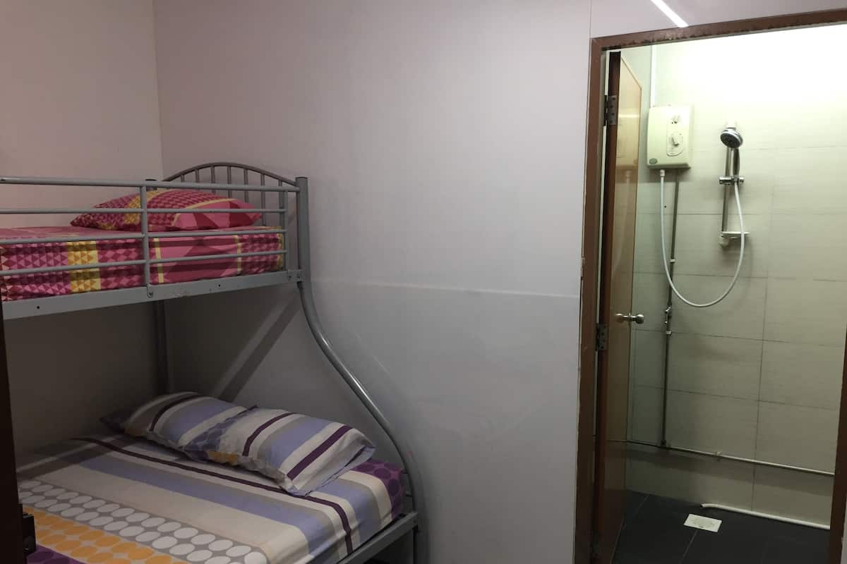 A bunk bed with patterned bedding, a shower area with a glass door, and a tiled floor.