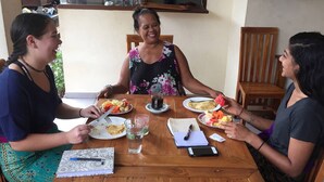 A wooden dining table with plates of food, a cup of tea, and a notebook. - Nyoman Badri Homestay (Ubud)