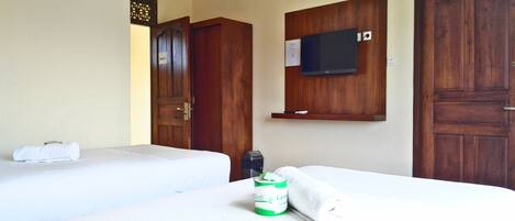 A hotel room with two beds, a television mounted on the wall, and a wooden door.