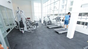 Une salle de sport équipée de matériel d’exercice, dotée de grandes fenêtres et présentant un design moderne.