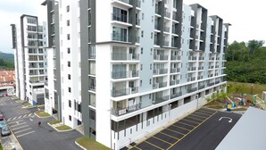 Un immeuble résidentiel à plusieurs étages, doté de balcons, d’un espace de stationnement et d’un terrain de jeux.