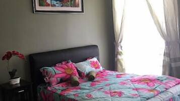 A bedroom with a bed, a nightstand, a framed picture, and a window with curtains.
