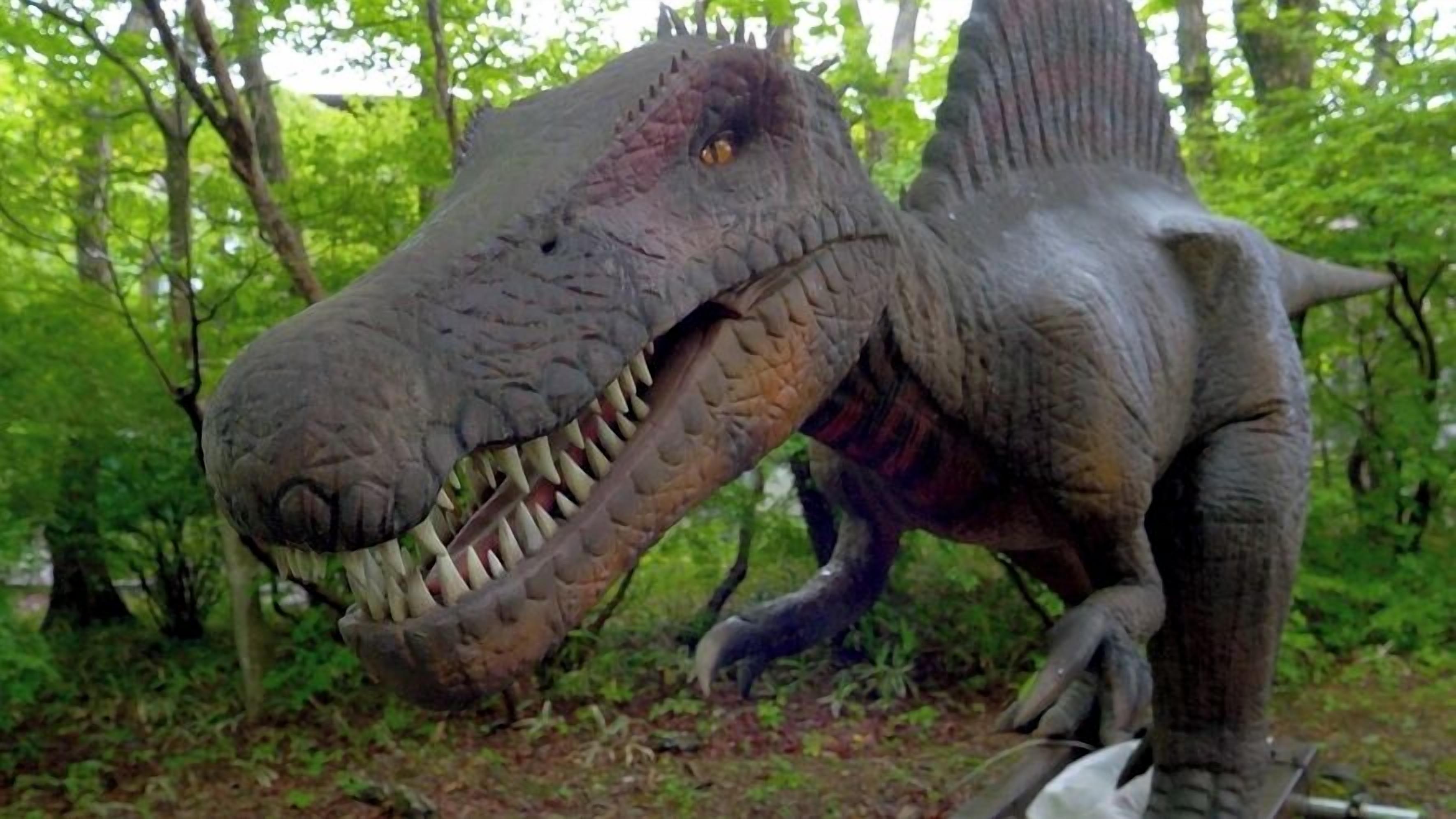 A large dinosaur statue in a forested area.