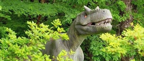A dinosaur statue surrounded by lush green foliage.