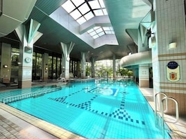 Una piscina interna con piastrelle blu trasparenti, un soffitto con finestra a soffitto e un muro rivestito di piastrelle con una targa.