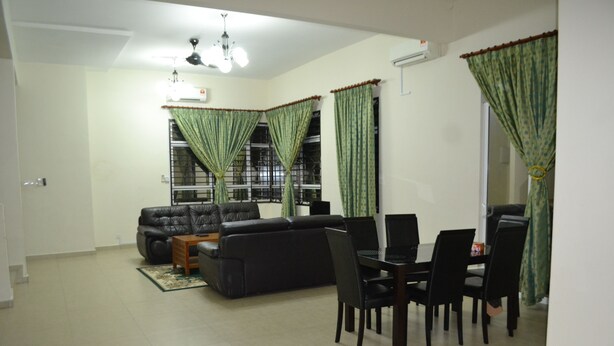 A living room with a sofa, dining table, chairs, and curtains. - Sitiyam Homestay Kota Warisan (Sepang)